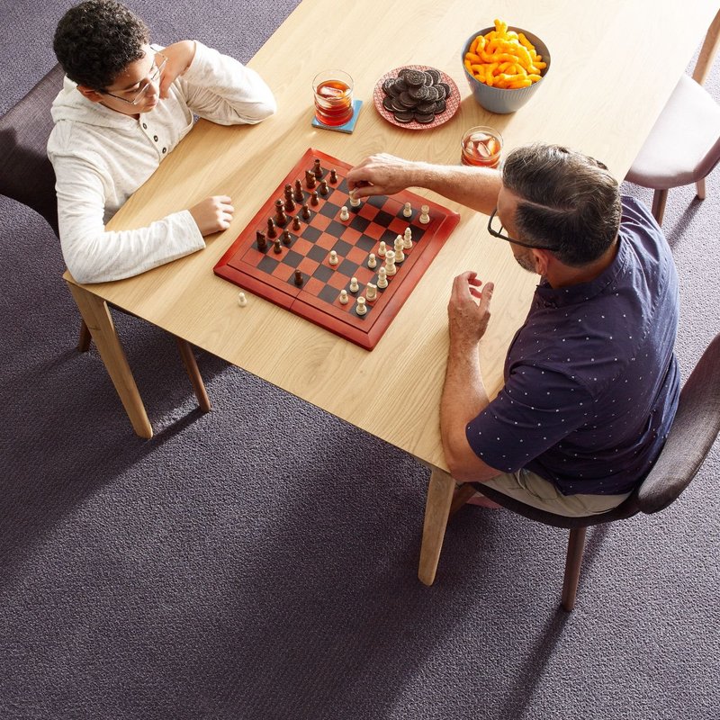 Two People Sitting At A Table And Playing Chess from King Carpet Plus in Plainview